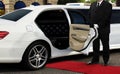 Driver standing next to opened car door with red carpet Royalty Free Stock Photo