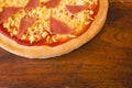 Cheap 12 inch Ham and cheese pizza made with par-baked dough, ham, tomato sauce and processed cheese. On a wood tray Royalty Free Stock Photo