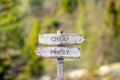 cheap pricey text carved on wooden signpost outdoors in nature.