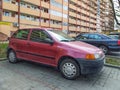 Purple red old small Italian compact car Fiat Punto parked