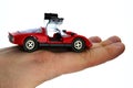 Cheap red plastic model of street-legal vintage racing car with opened gullwing doors, held in on back of hand of adult man. Royalty Free Stock Photo