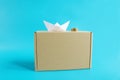 Cheap shipping cargo concept. Paper ship, coins and craft box front view isolated blue background