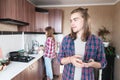 Cheating wife. The young man looks suspiciously at his wife who washes the dishes. The man has his smartphone in his Royalty Free Stock Photo
