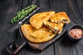 Cheburek meat pastry pie with herbs. Black wooden background. Top view