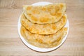 Chebureks with meat or pie of yellow appetizing color on a white round plate on a wooden board background. Bakery products Royalty Free Stock Photo