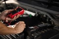 Check battery voltage with electric multimeter. Man using multimeter to measure the voltage of the batteries. Mechanic Royalty Free Stock Photo