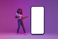 Check This. Cheerful Black Female Pointing At Blank Smartphone In Neon Light Royalty Free Stock Photo