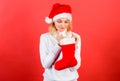 Check contents of christmas stocking what she received. Woman in santa hat unpacking christmas gift red background Royalty Free Stock Photo