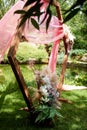 Check-in in the forest by the lake.A diamond-shaped arch of wood decorated with pampas, pink chiffon. Wedding floristry.