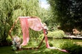 Check-in in the forest by the lake.A diamond-shaped arch of wood decorated with pampas, pink chiffon. Wedding floristry.