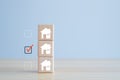 Check mark select house icon on wooden block. Decision to choose best property.