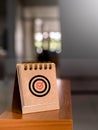 Check mark sign, correct icon at center of target dart symbol on brown small desk calendar cover.