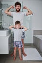 Check out these babies. Portrait of a father and his little son flexing their arms in the bathroom at home.