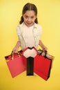 Check out her profitable purchases. Girl carries shopping bags yellow background. Girl fond of shopping. Child cute Royalty Free Stock Photo