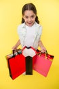 Check out her profitable purchases. Girl carries shopping bags yellow background. Girl fond of shopping. Child cute Royalty Free Stock Photo