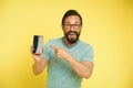 Check out new app. Guy eyeglasses cheerful pointing at smartphone. Man happy user recommends try application for Royalty Free Stock Photo