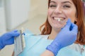 Check and select the color of the teeth in the dentist chair. Dentist makes the process of treating a beautiful young red-haired