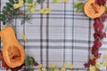 checkered beige autumn background with edible cut pumpkin and crimson yellow leaves