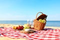 Checkered blanket with picnic basket and products on sunny Royalty Free Stock Photo