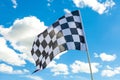 Checkered flag on flagpole with white clouds on background Royalty Free Stock Photo