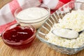 Napkin, bowls with sour cream and raspberry jam, spoon with sour cream in bowl with cottage cheese on table Royalty Free Stock Photo