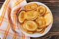 Napkin, heap of pancakes in white plate on wooden table. Top view