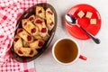 Napkin, shortbread cookies with jam in brown dish, cup with tea, sugar and teaspoon on saucer on table. Top view Royalty Free Stock Photo