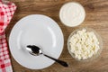 Napkin, spoon in plate, transparent bowls with sour cream and cottage cheese on wooden table. Top view Royalty Free Stock Photo