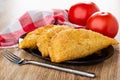 Napkin, tomatoes, fried cheburek in brown dish, fork on wooden table