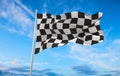 Checkered racing Flag waving in the wind on flagpole against the sky with clouds on sunny day Royalty Free Stock Photo