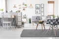 Checkered, stylish chair on a gray rug in a spacious, scandinavian living room interior with mock-up gallery above a sofa