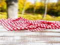 Checkered tablecloth on old wooden table on blurred park background, holiday concept