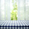 Checkered tablecloth texture top on blur of curtain with window view green from tree garden background Royalty Free Stock Photo