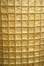 Checkered texture of the glass blocks. Golden-colored glass or mosaic smalt with yellow filling of seams. Abstract