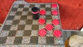 Checkers anyone?! Outdoor cloth board with large red and black checkers. Red wood wall. Competition.