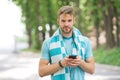 Checking all training updates. Man athlete setting up fitness tracker with smartphone app, nature background. Sportsman Royalty Free Stock Photo