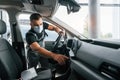 Checking control panel. Man in uniform is working in the autosalon at daytime