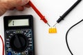Checking functionality of colored automotive fuses with digital multimeter on white background