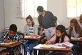 Checking on her class progress. a young teacher helping her students with their homework in class.