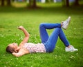 Checking in with her friends. a young woman using her cellphone while lying on the grass at a park. Royalty Free Stock Photo