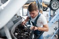 Checking if everything connected correctly. Employee in the blue colored uniform works in the automobile salon Royalty Free Stock Photo