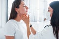 Checking lymph nodes and throat. Young woman have a visit with female doctor in modern clinic