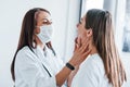 Checking lymph nodes and throat. Young woman have a visit with female doctor in modern clinic