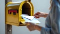 Checking Mail: A Person Retrieving Letters from a Bright Yellow Mailbox Royalty Free Stock Photo
