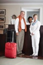 Checking in at reception. A senior couple checking in at the reception desk of their hotel. Royalty Free Stock Photo