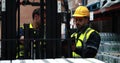 Checking tablet, worker in yellow hard hat and hi-vis vest operating forklift in warehouse Royalty Free Stock Photo