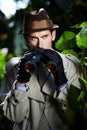 Checking up on you.... Private investigator using binoculars to spy on someone from the bushes. Royalty Free Stock Photo