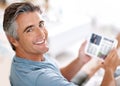 Checking whats online. Cropped portrait of a handsome mature man using a tablet while sitting on his living room sofa. Royalty Free Stock Photo