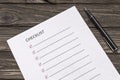 Checklist, pen on the background of a wooden table. Royalty Free Stock Photo