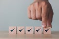 Checklist Survey and assessment concept, human hand putting cube wood with Check mark icon on wooden blocks, gray background